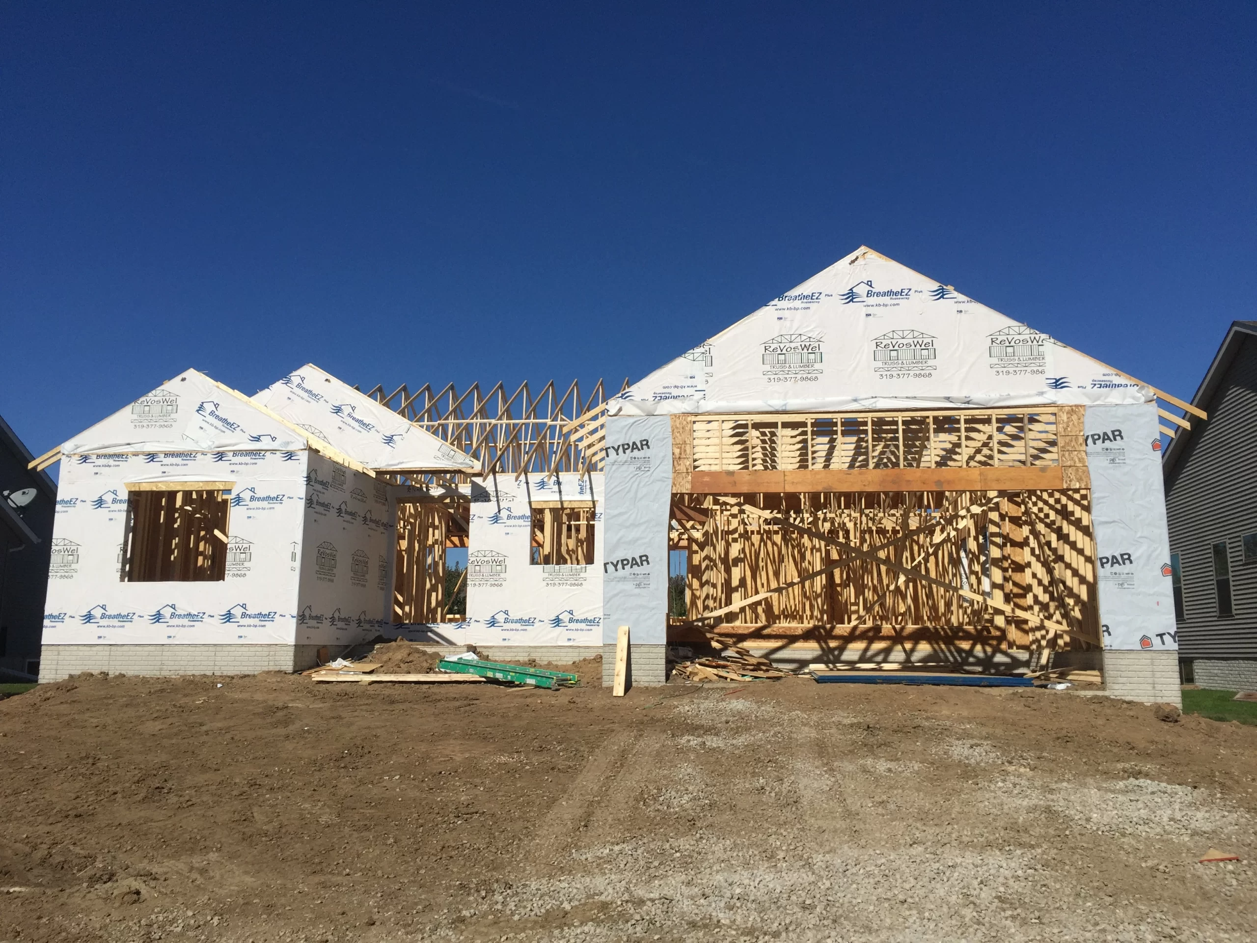 Front view of a nearly completed custom home framing with exterior barrier wrap installed.